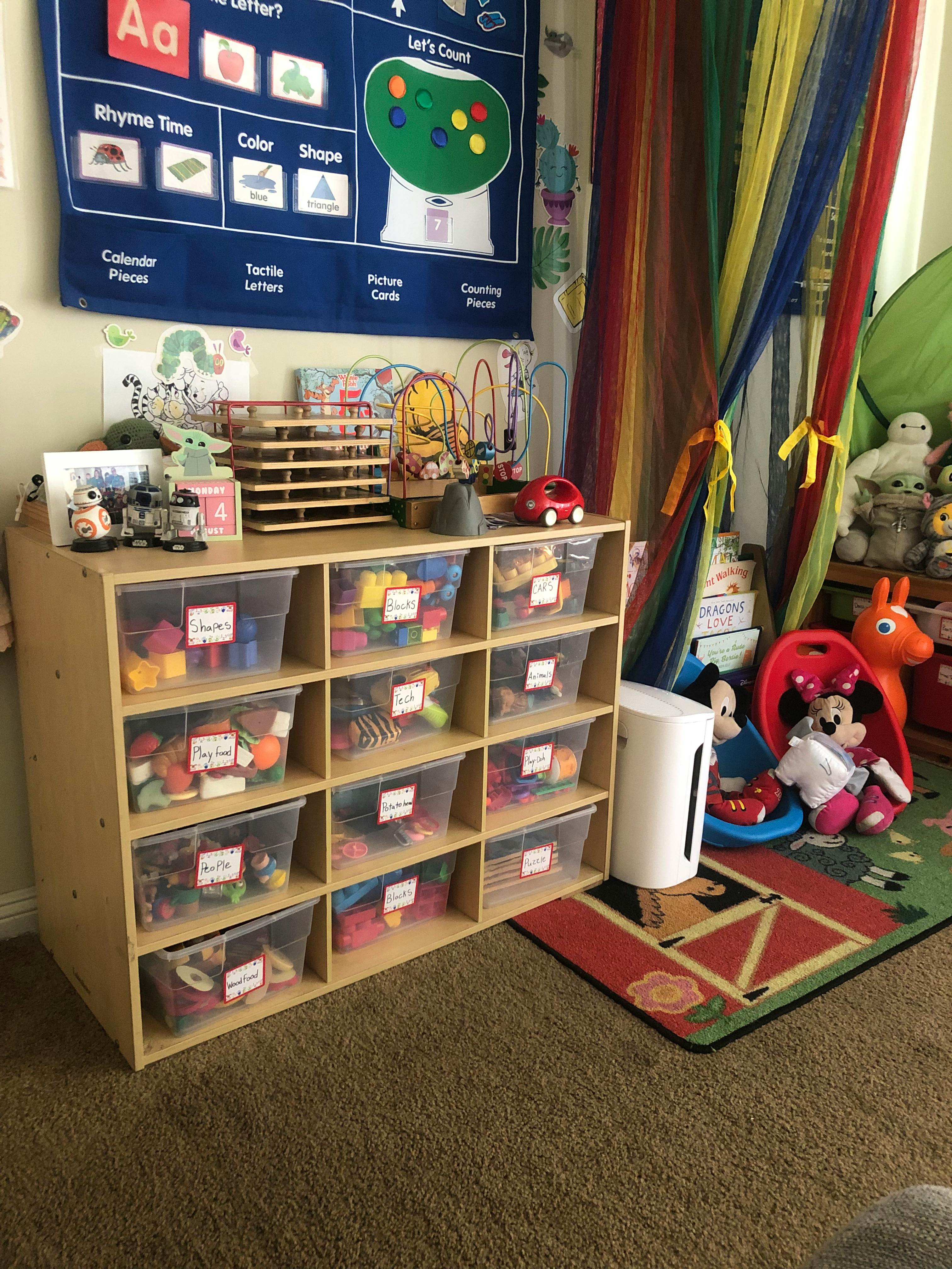 Toy storage shelf with clear bins filled with toys in a child's room