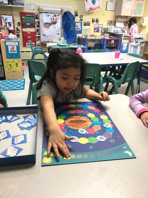 Child playing a board game in a classroom