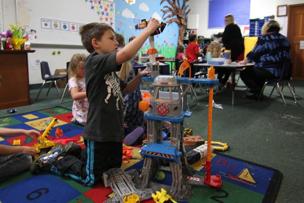 Child playing with a toy structure in a classroom