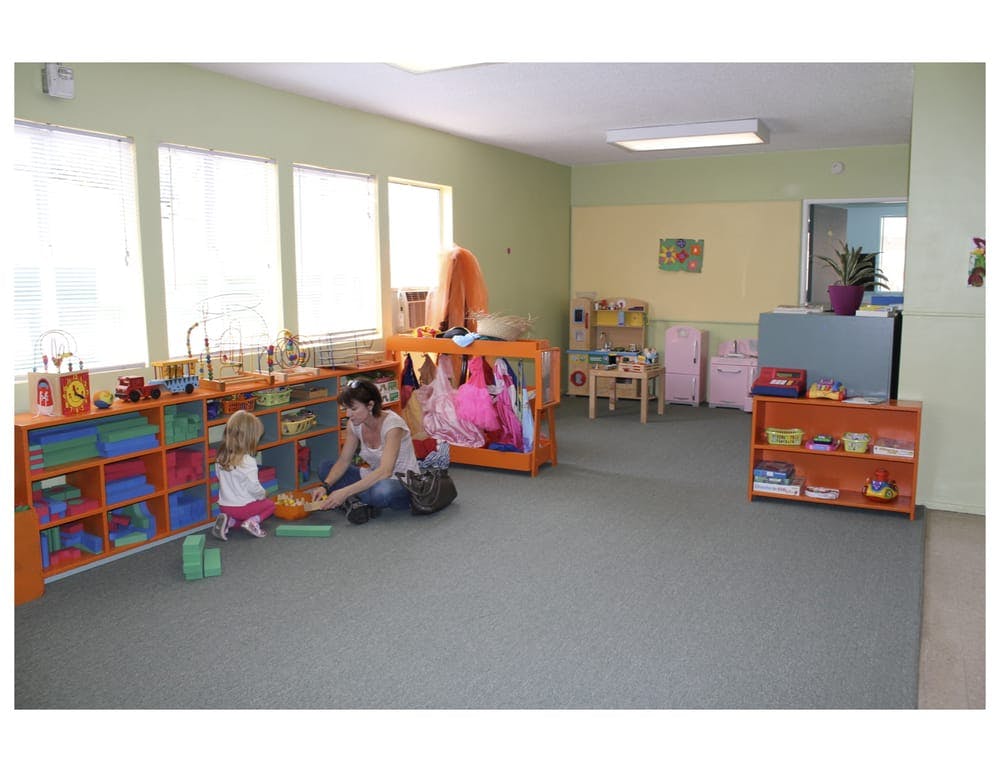 Adult and child playing with blocks on the floor in a classroom