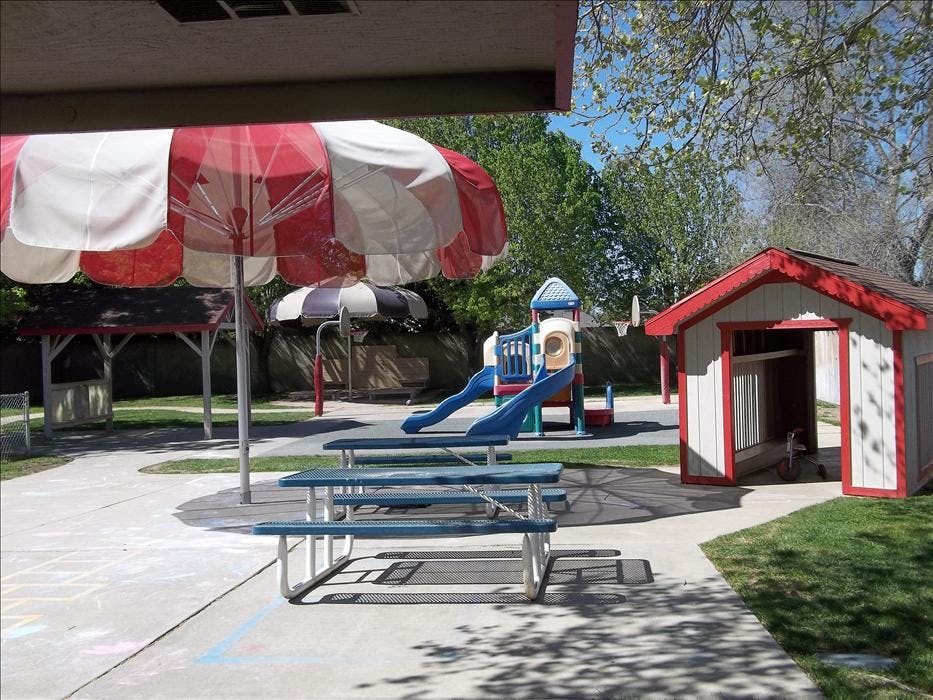 Playground with slides, playhouse, picnic tables, and umbrellas