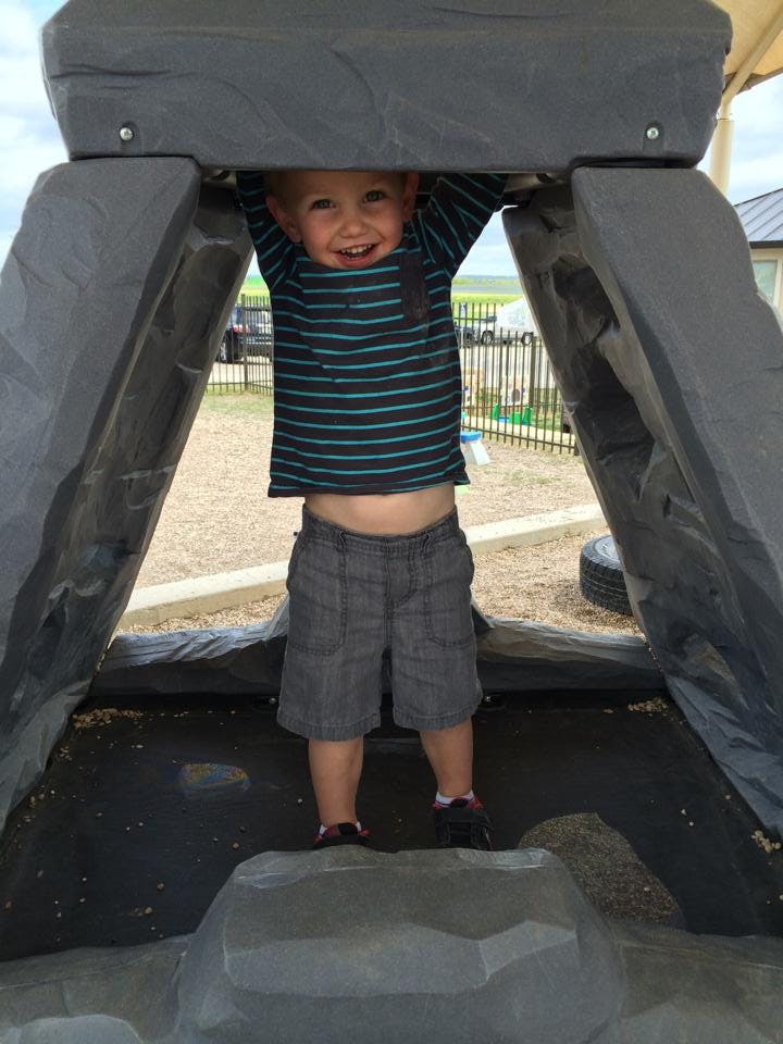 Child standing under a playground structure
