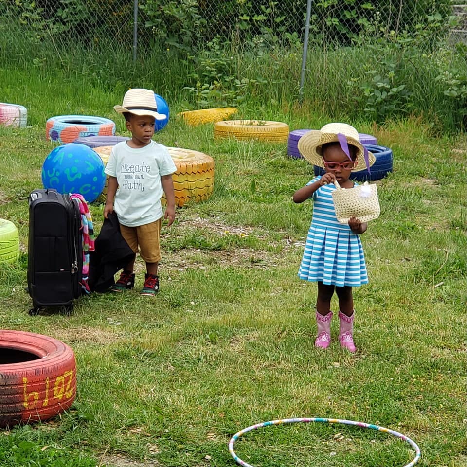 Two children playing outdoors with painted tires and a hula hoop