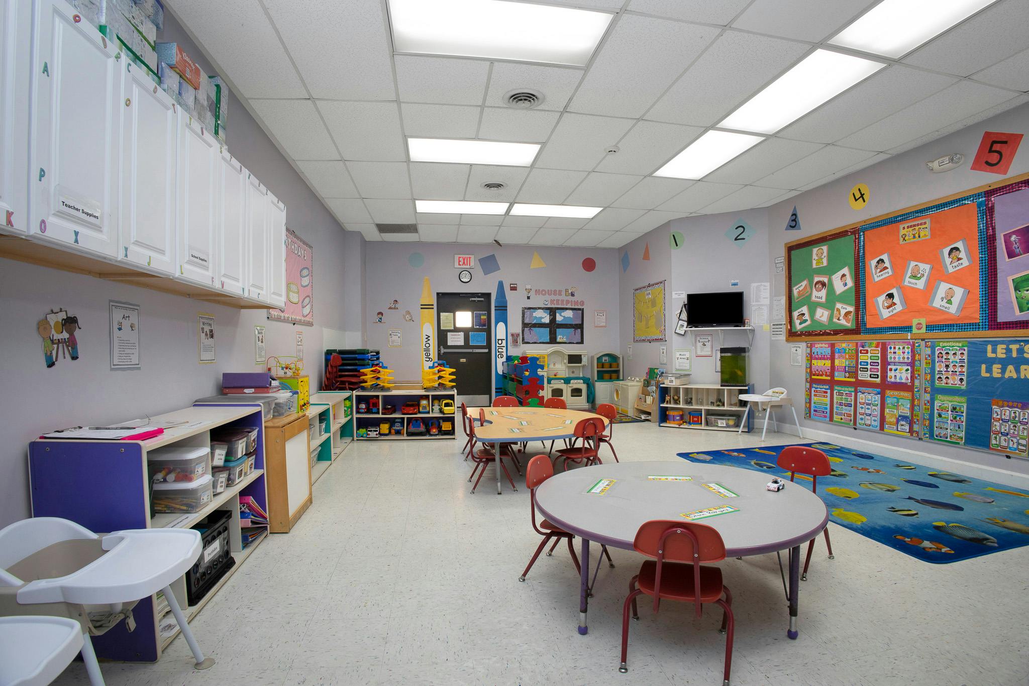Colorful classroom with tables and chairs for children, educational posters on walls