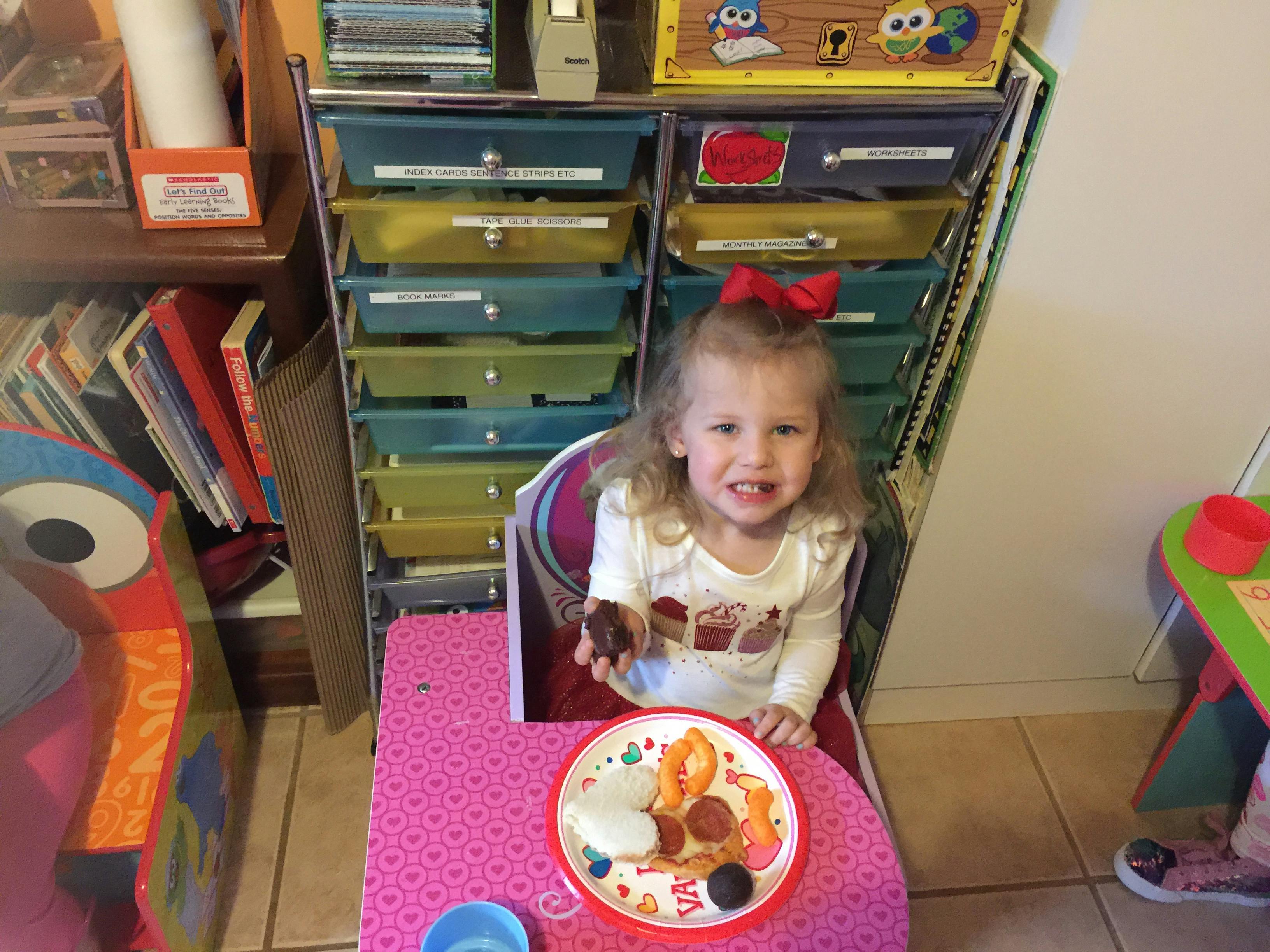 Child sitting at a small table eating a snack