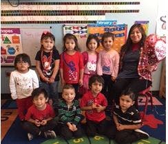 Adult and multiple children posing in a classroom