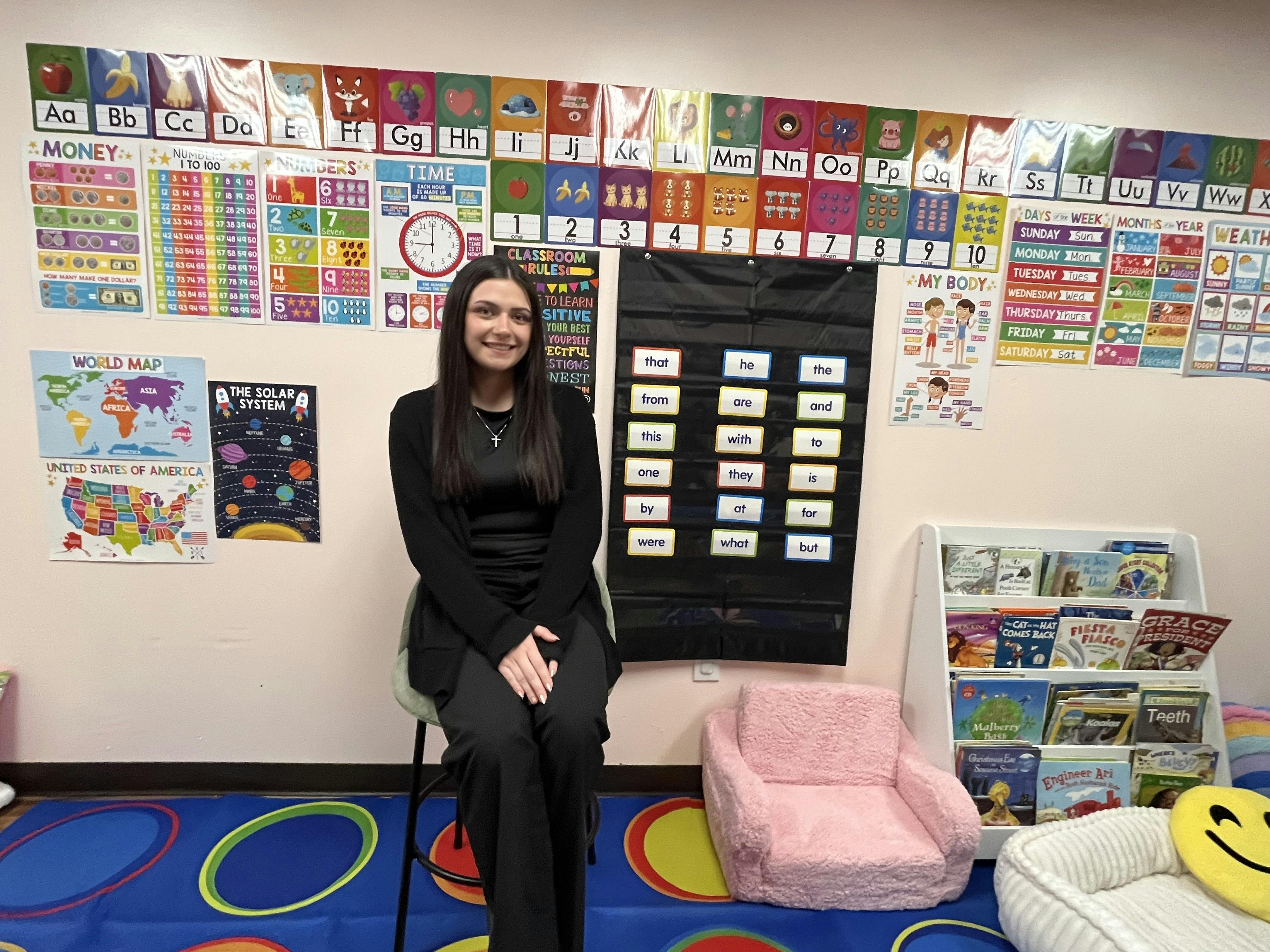 Person sitting in a classroom surrounded by educational posters