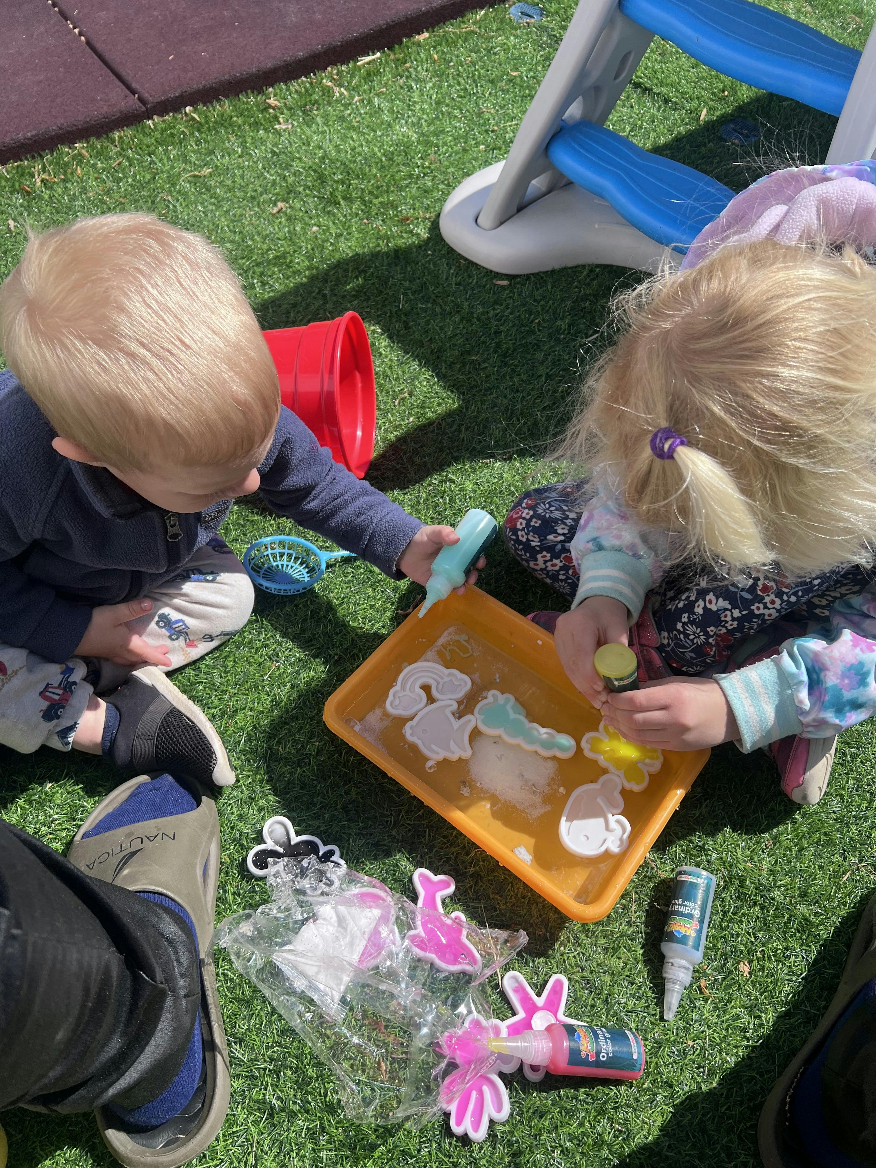 Two children playing with cookie cutters and craft supplies