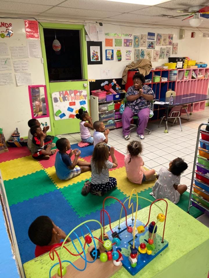 Adult and children sitting on floor in classroom
