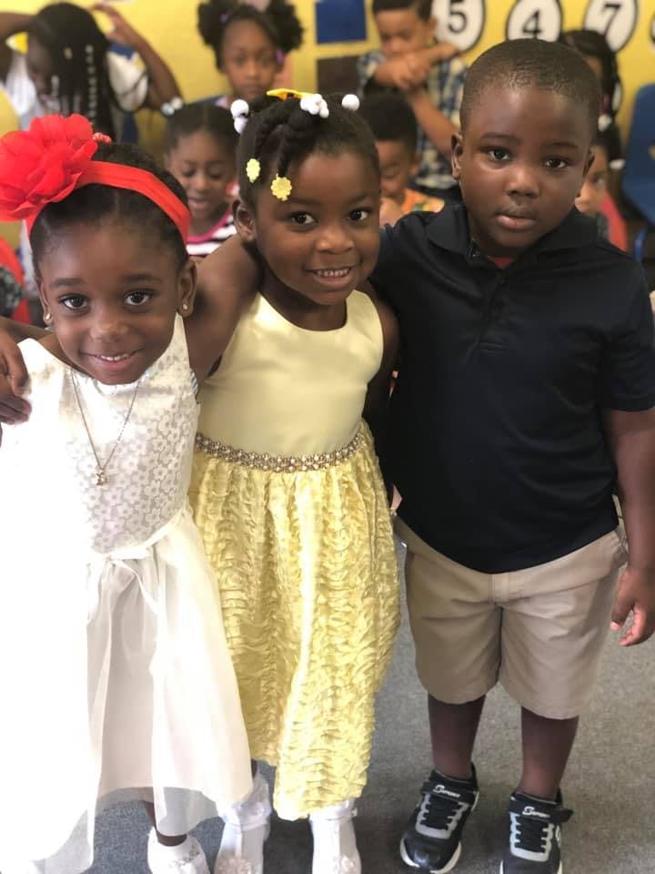 Three children standing together, two girls and one boy