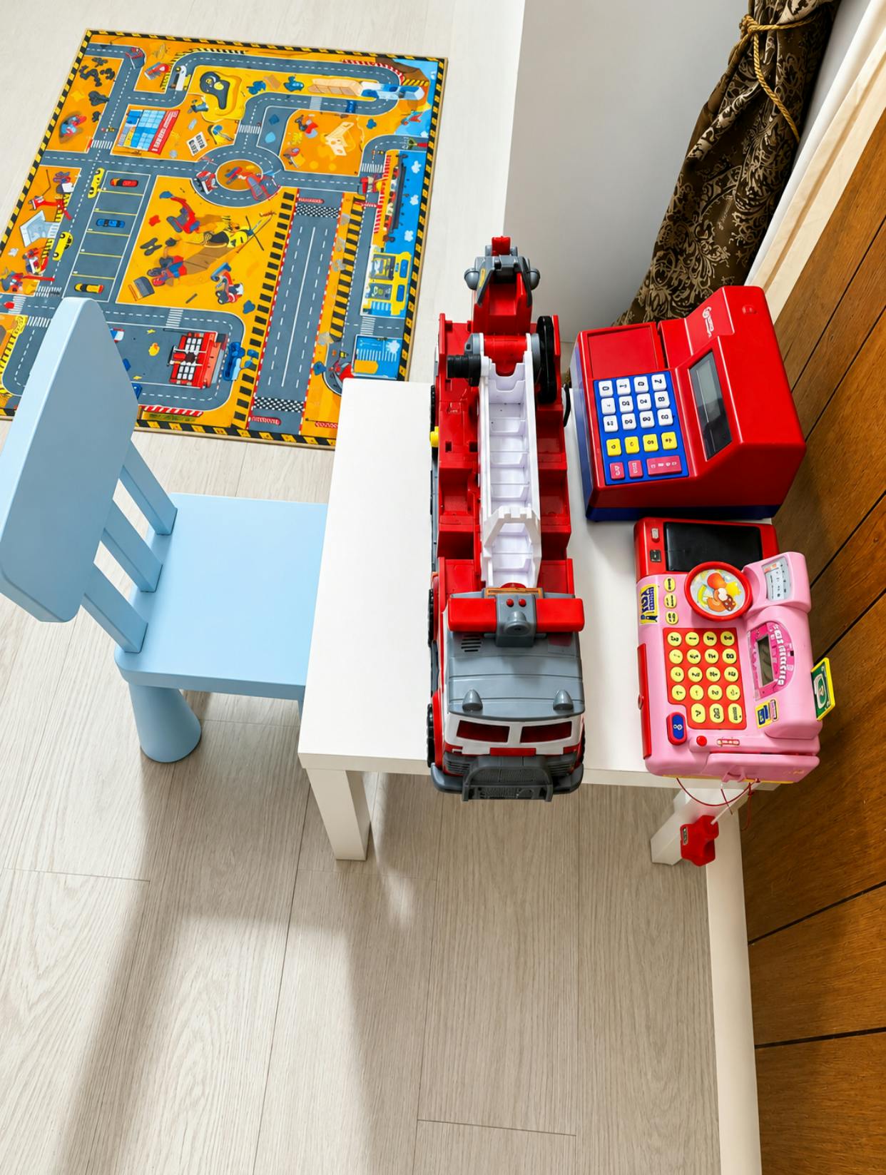 Toy fire truck and toy cash registers on a small table with a blue chair
