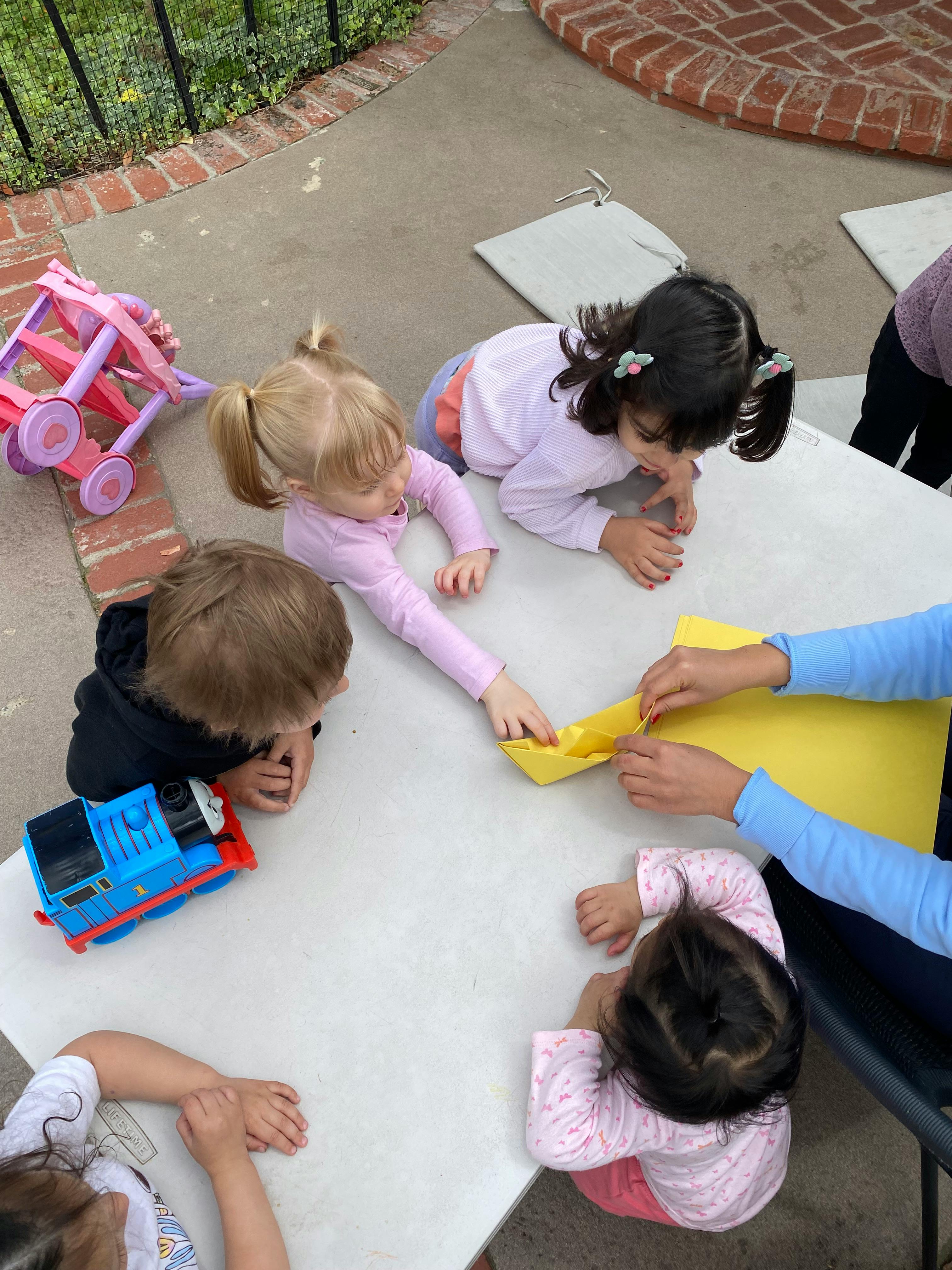 Children and an adult making paper crafts at a table