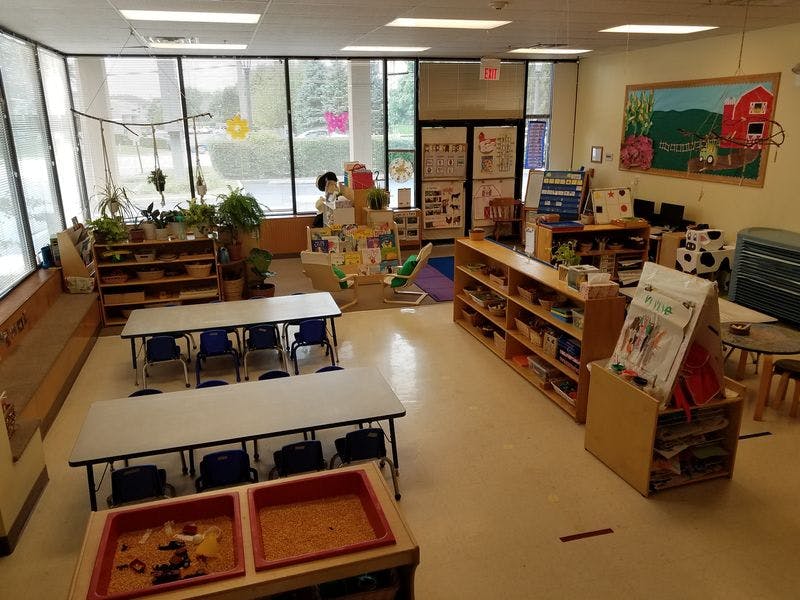 Classroom with tables, chairs, and shelves filled with learning materials