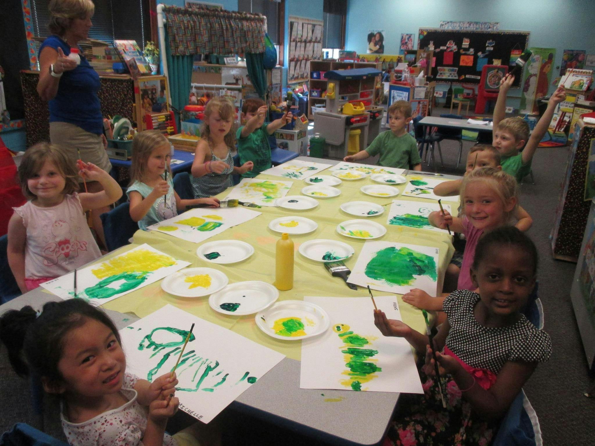 Children painting at a table in a classroom