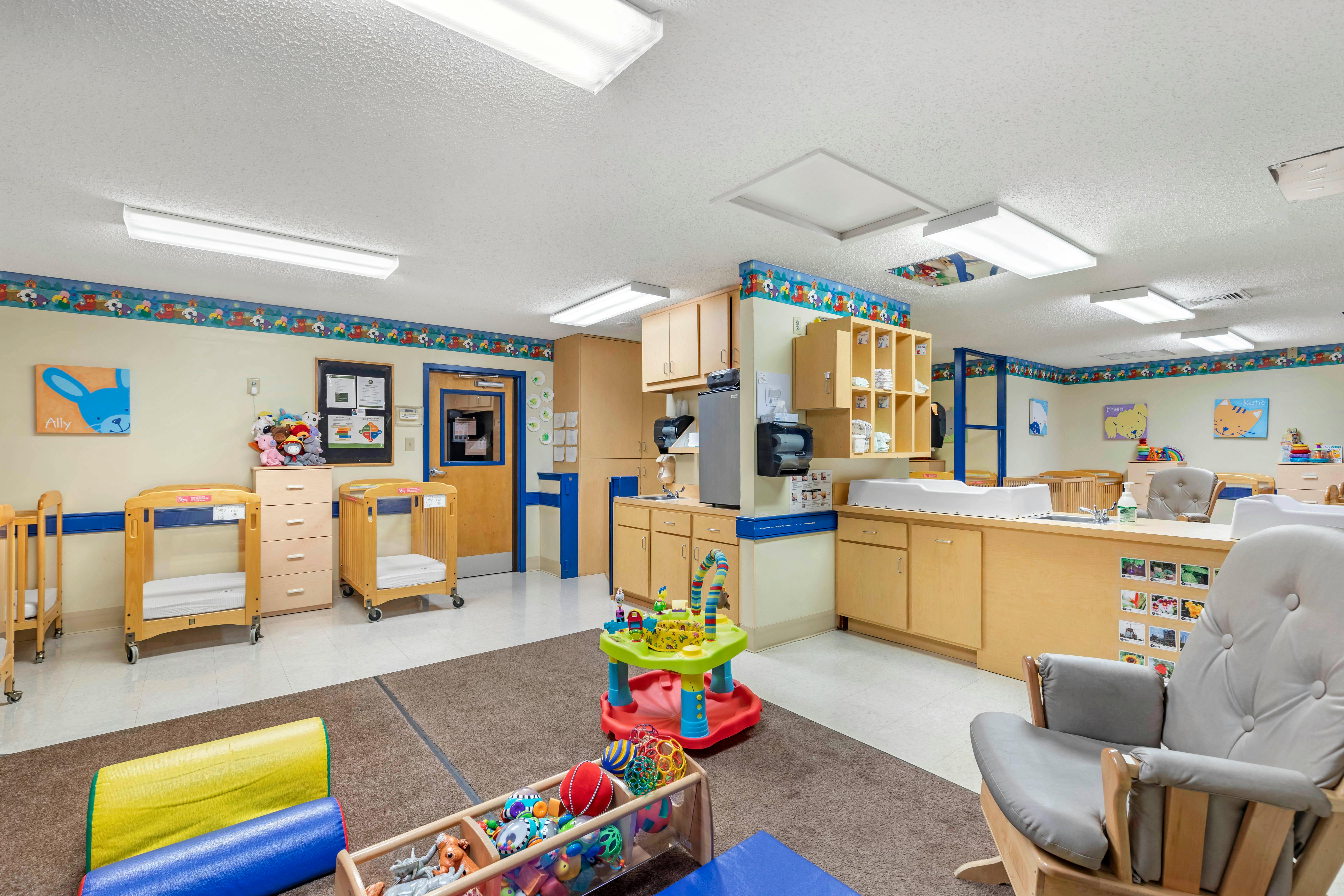 Baby room with cribs, changing stations, toys, and small kitchen