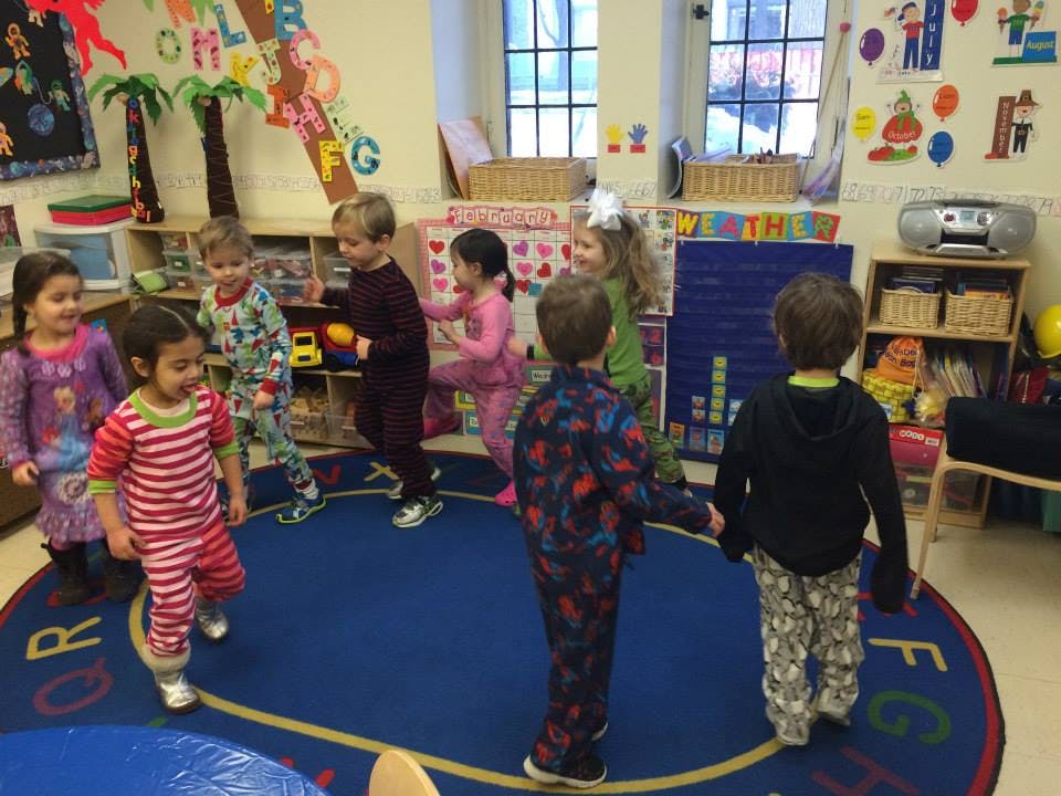 Children in pajamas playing in a circle in a classroom