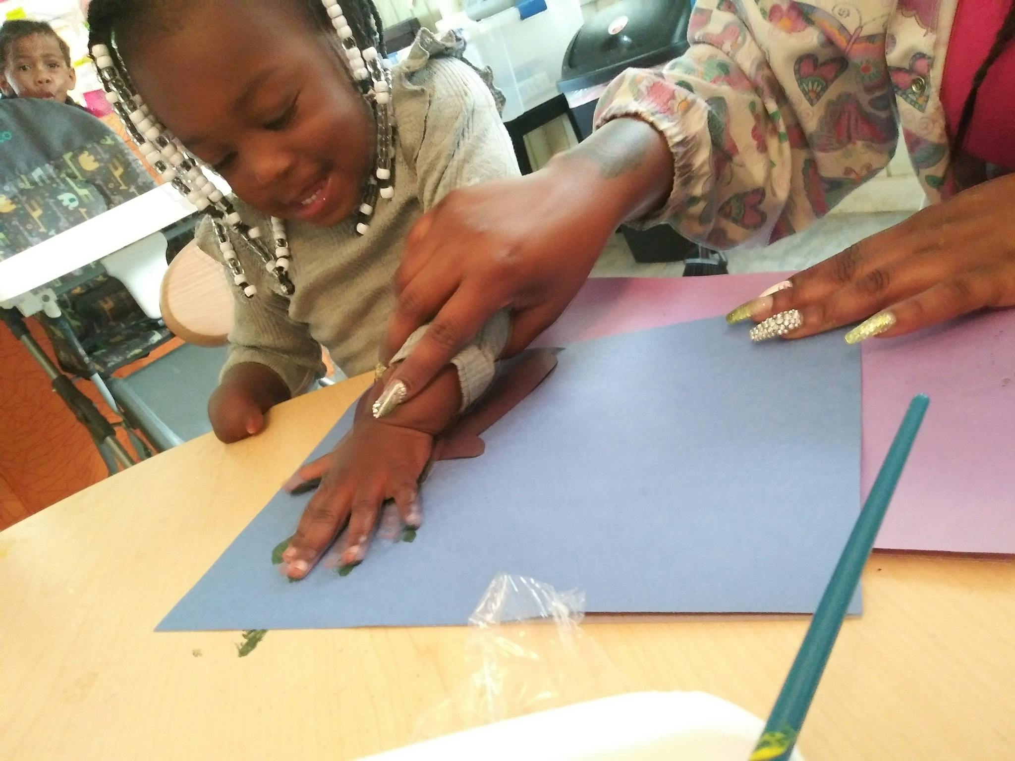 Adult helping child with an art project on a table