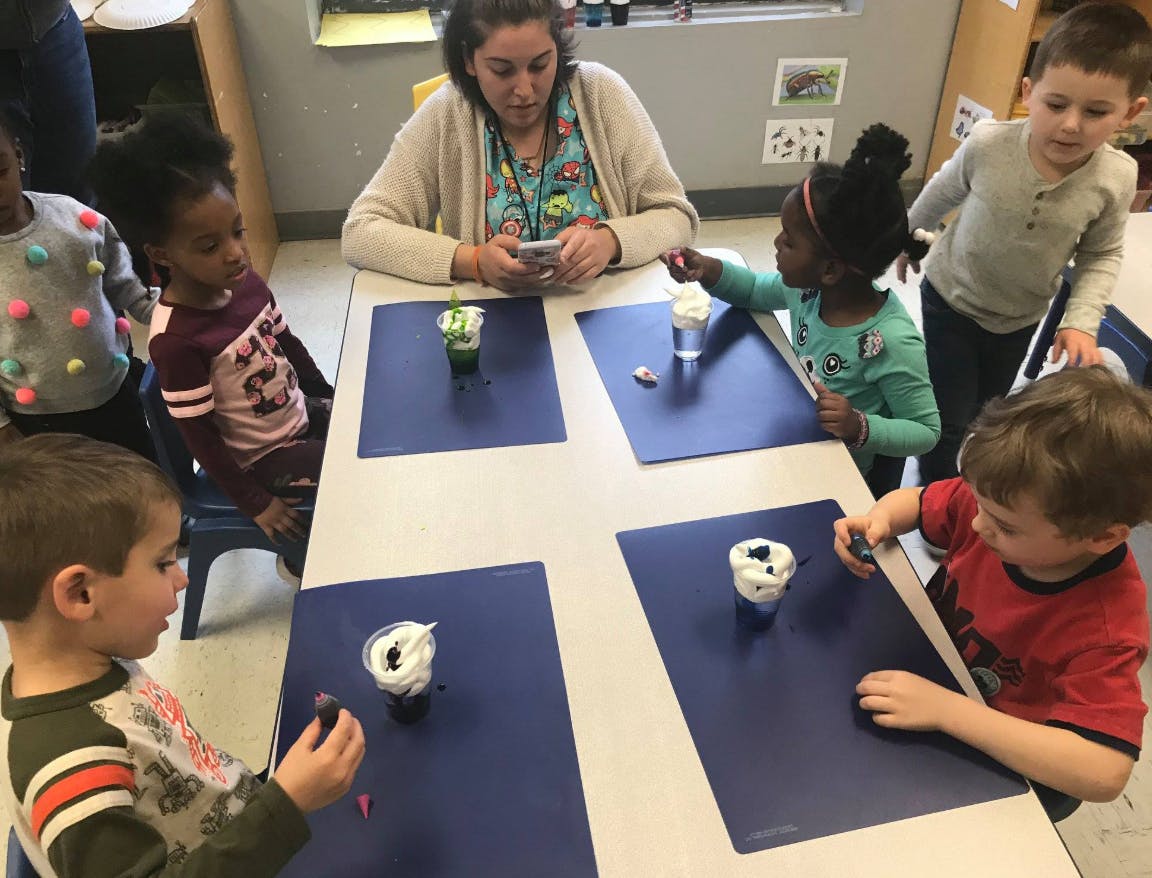Adult and children at a table with cups and blue placemats