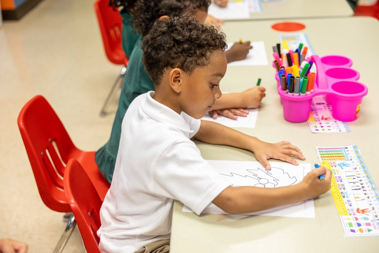 Child coloring at a desk in a classroom