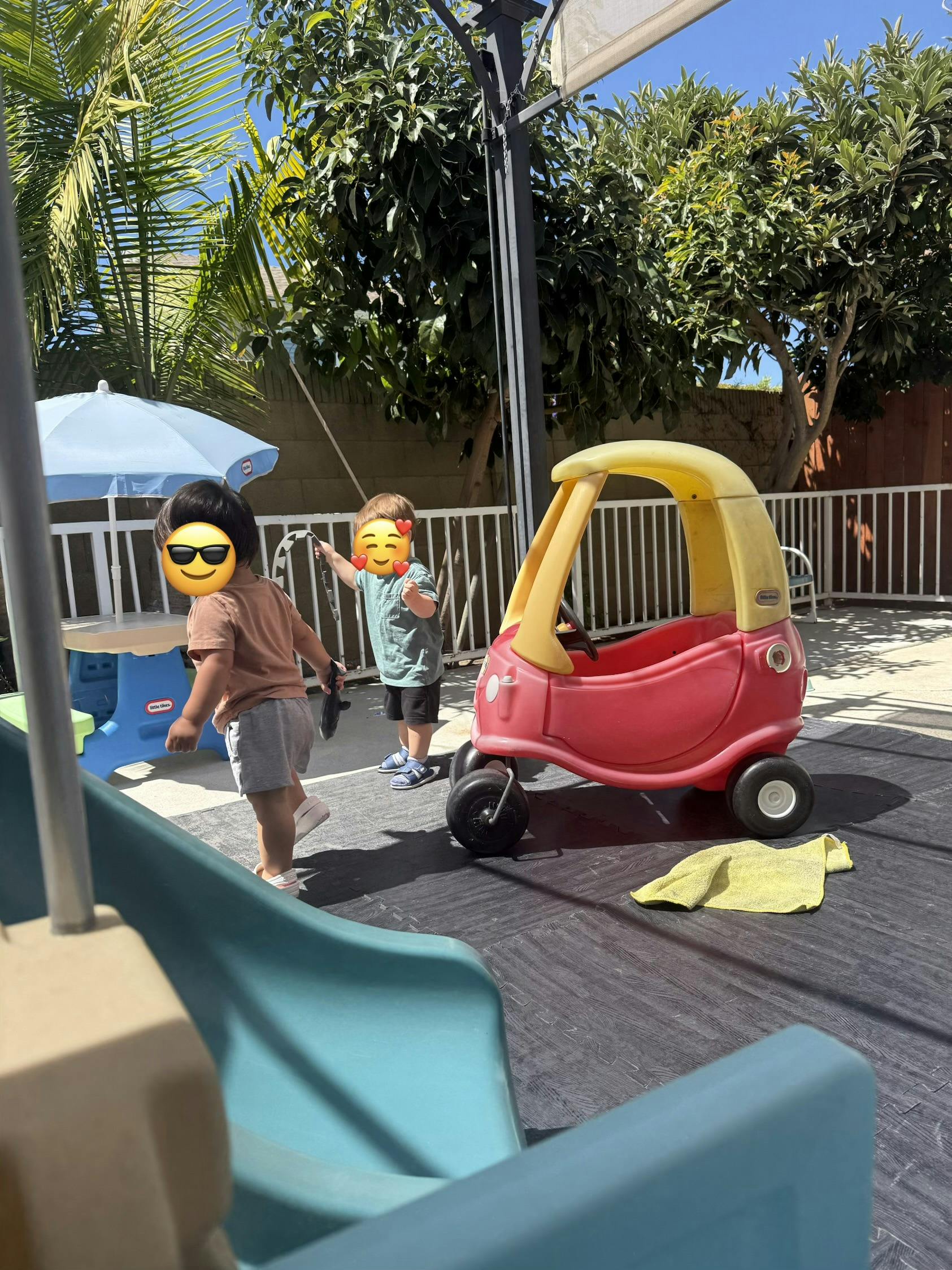 Two children playing with a toy car in an outdoor play area