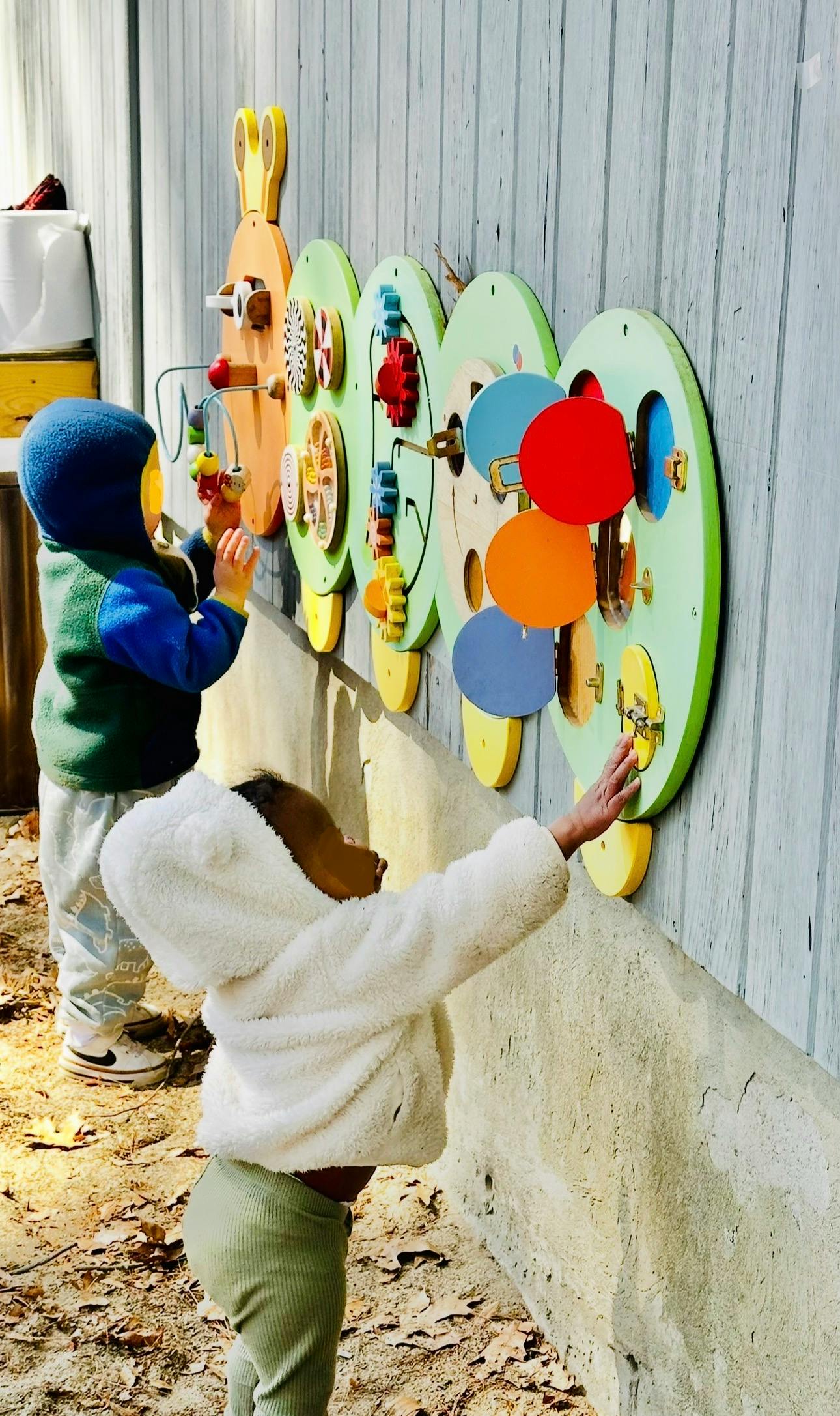 Two children playing with an outdoor activity board