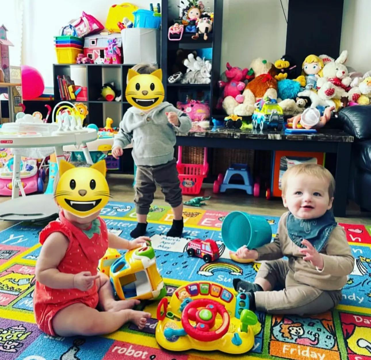 Three children playing with toys on a colorful mat