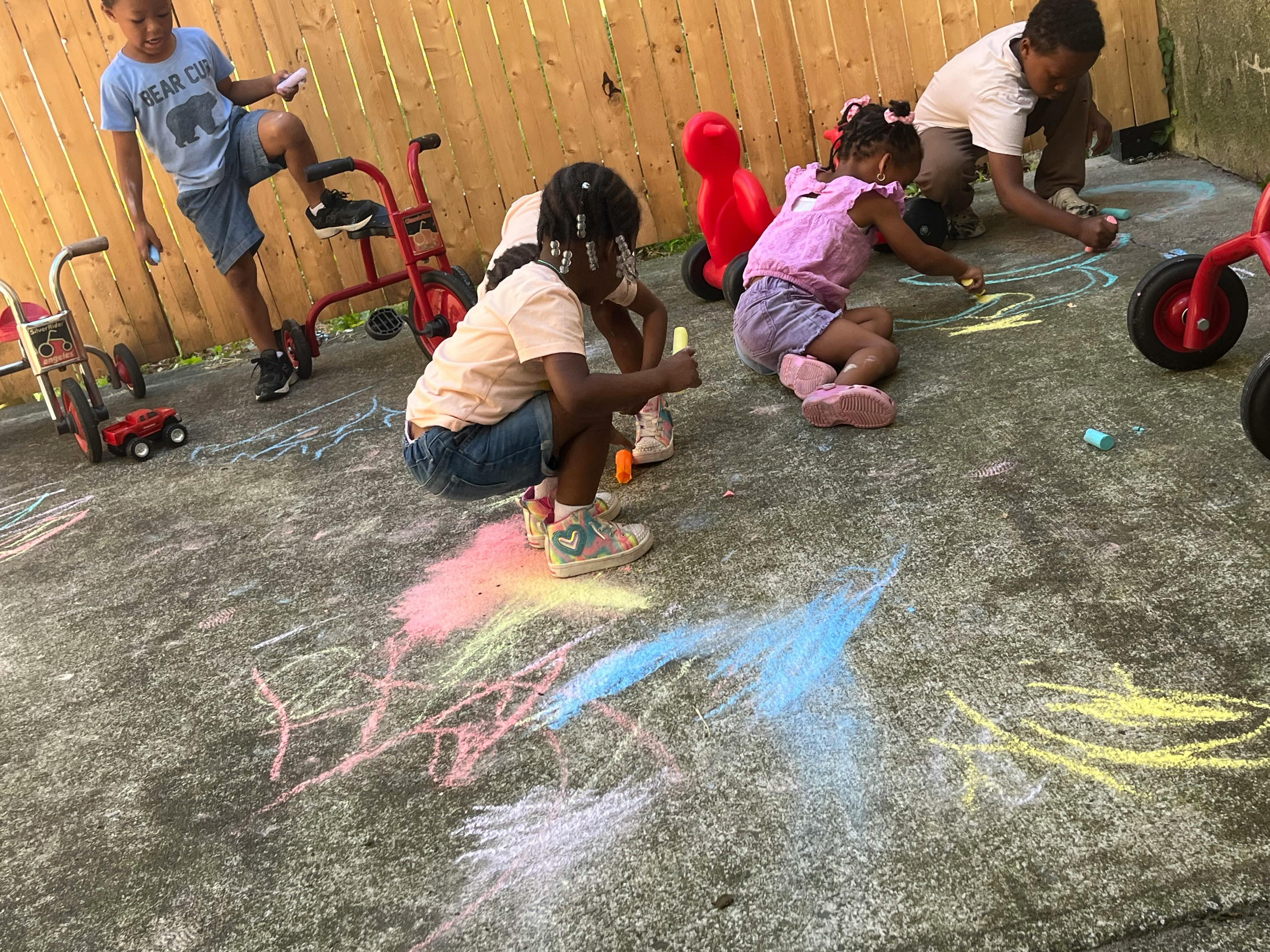Children drawing with chalk on pavement
