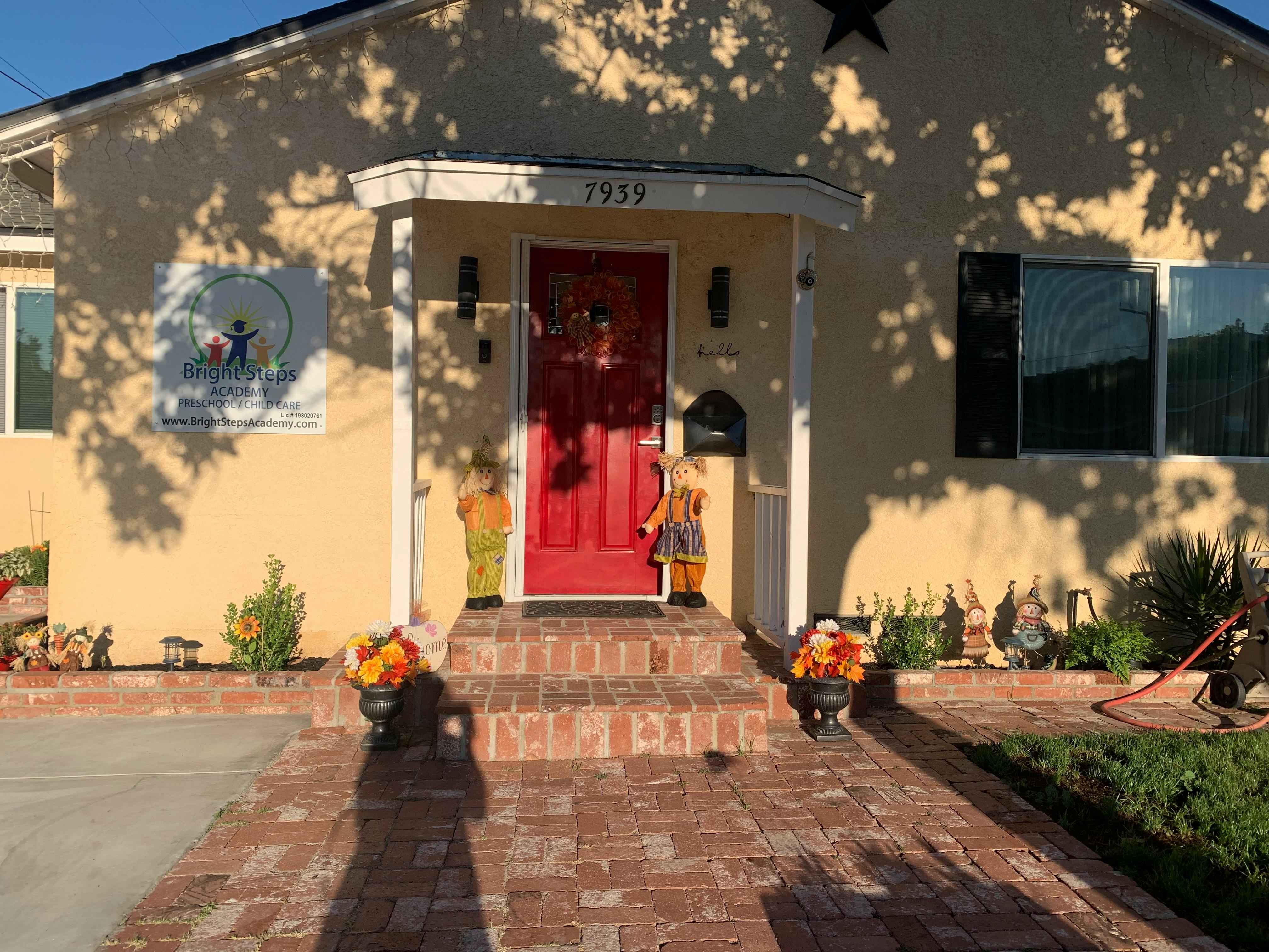 Front exterior of a house with a red door and brick walkway