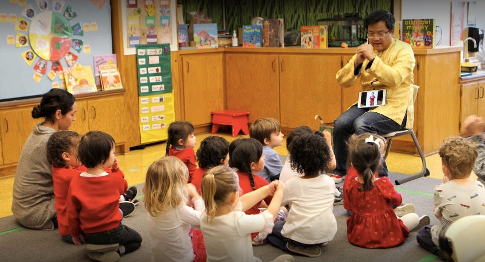 Adult speaking to a group of children sitting on the floor