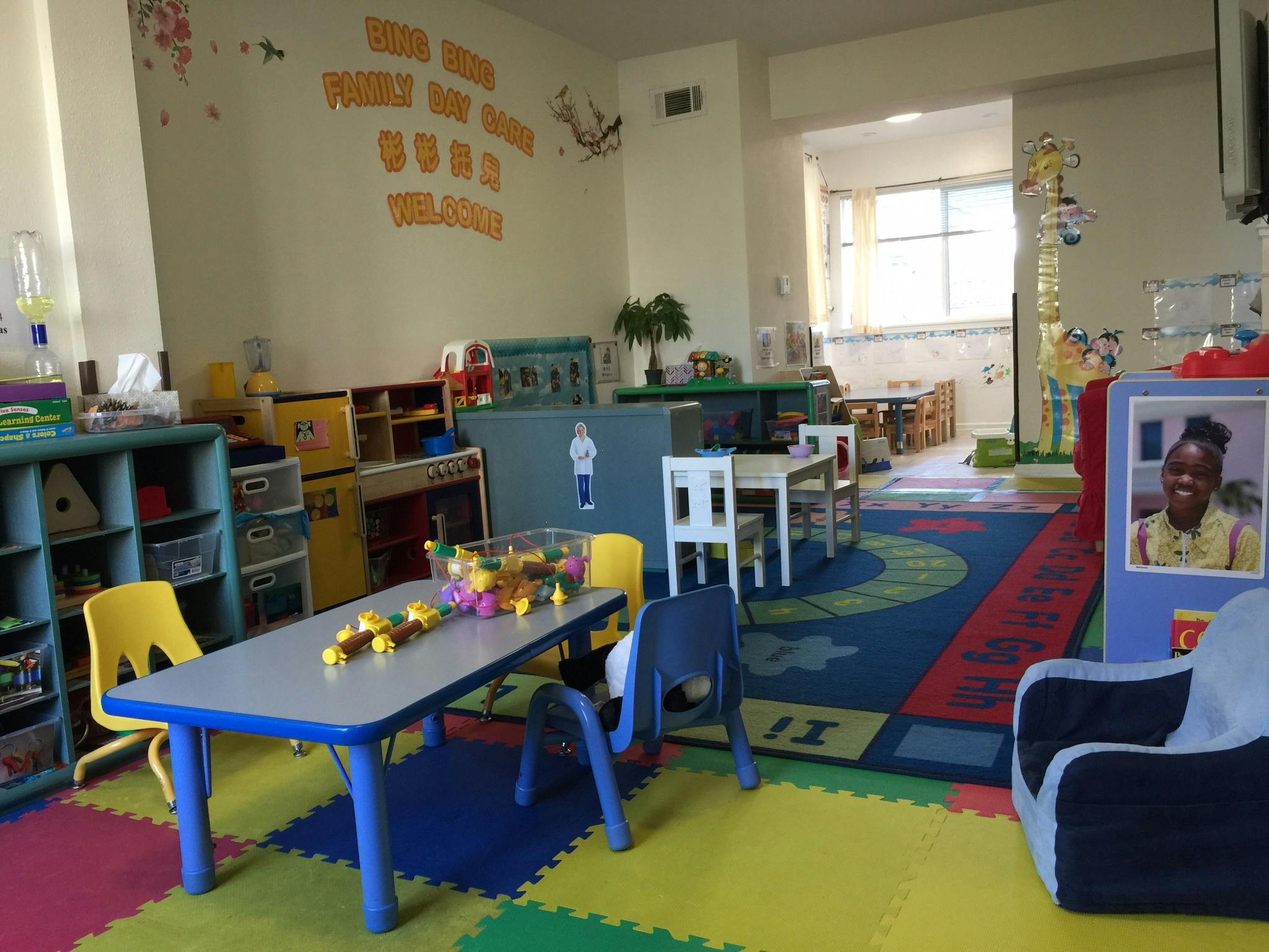 A colorful classroom with small tables and chairs, and a photo of a child
