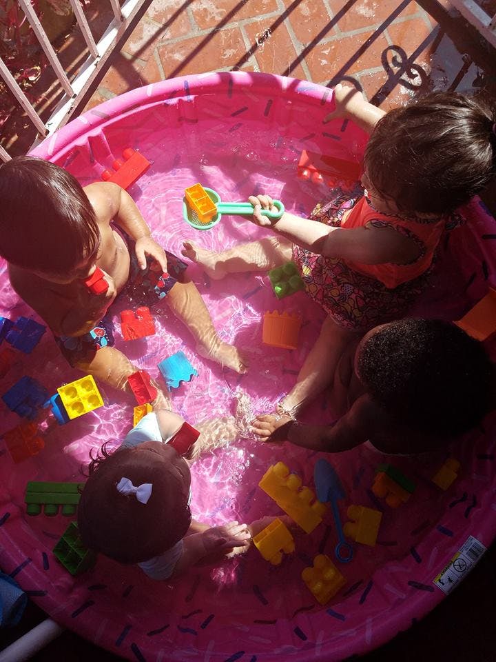 Children playing in a pink inflatable pool with toys