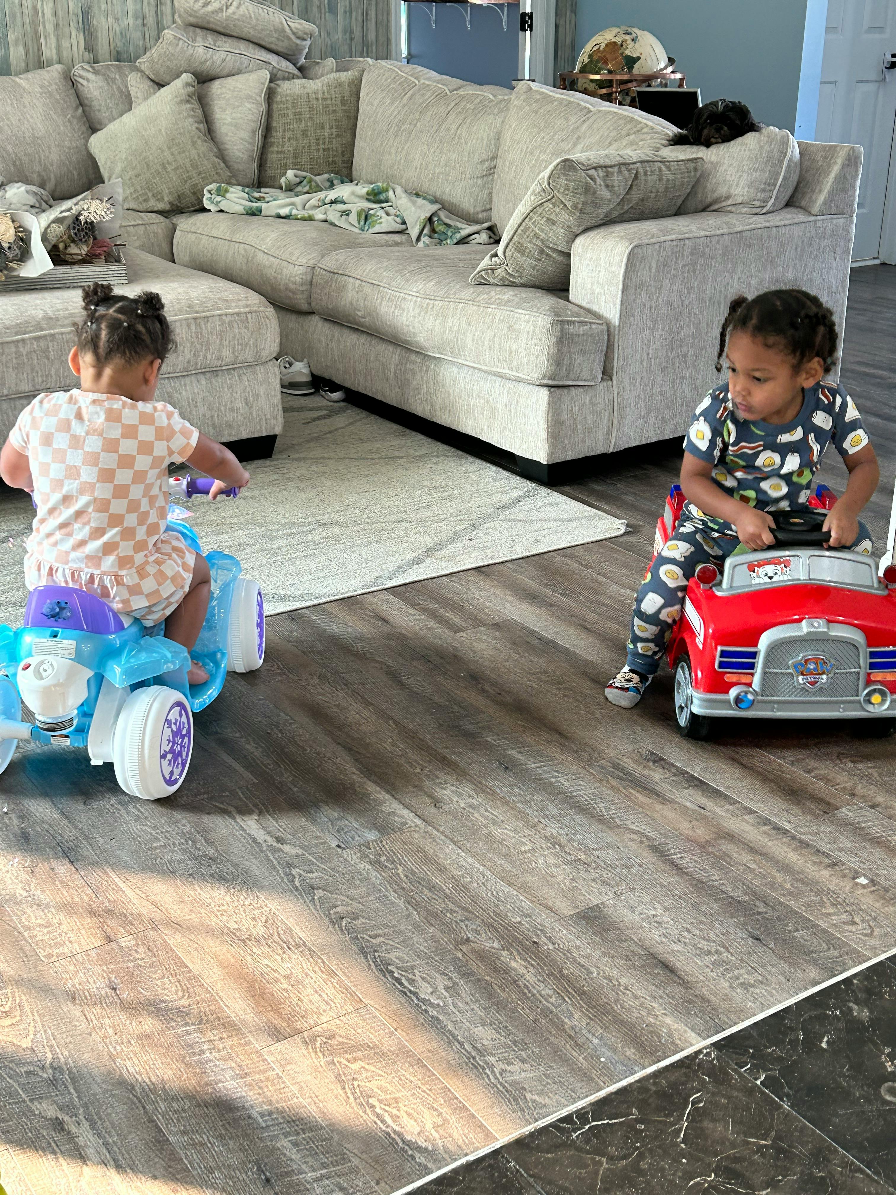Two children riding toy vehicles indoors