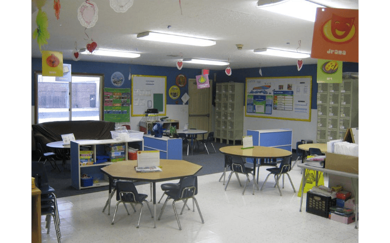 An empty classroom with tables, chairs, and colorful decorations