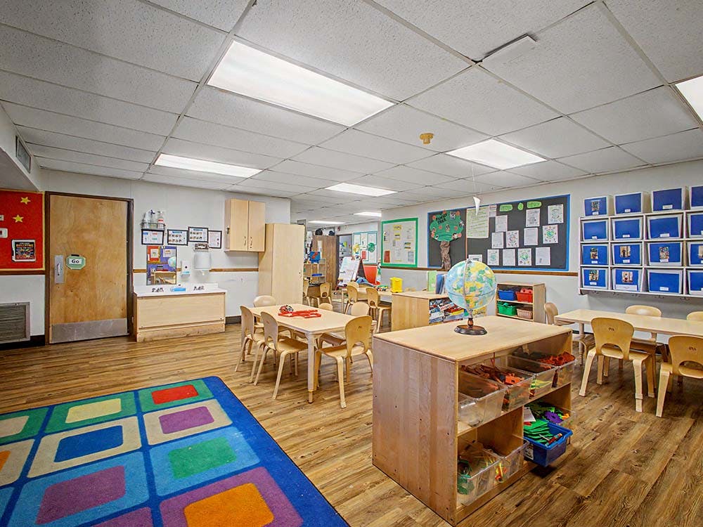 Classroom with small tables and chairs, a globe on a storage unit