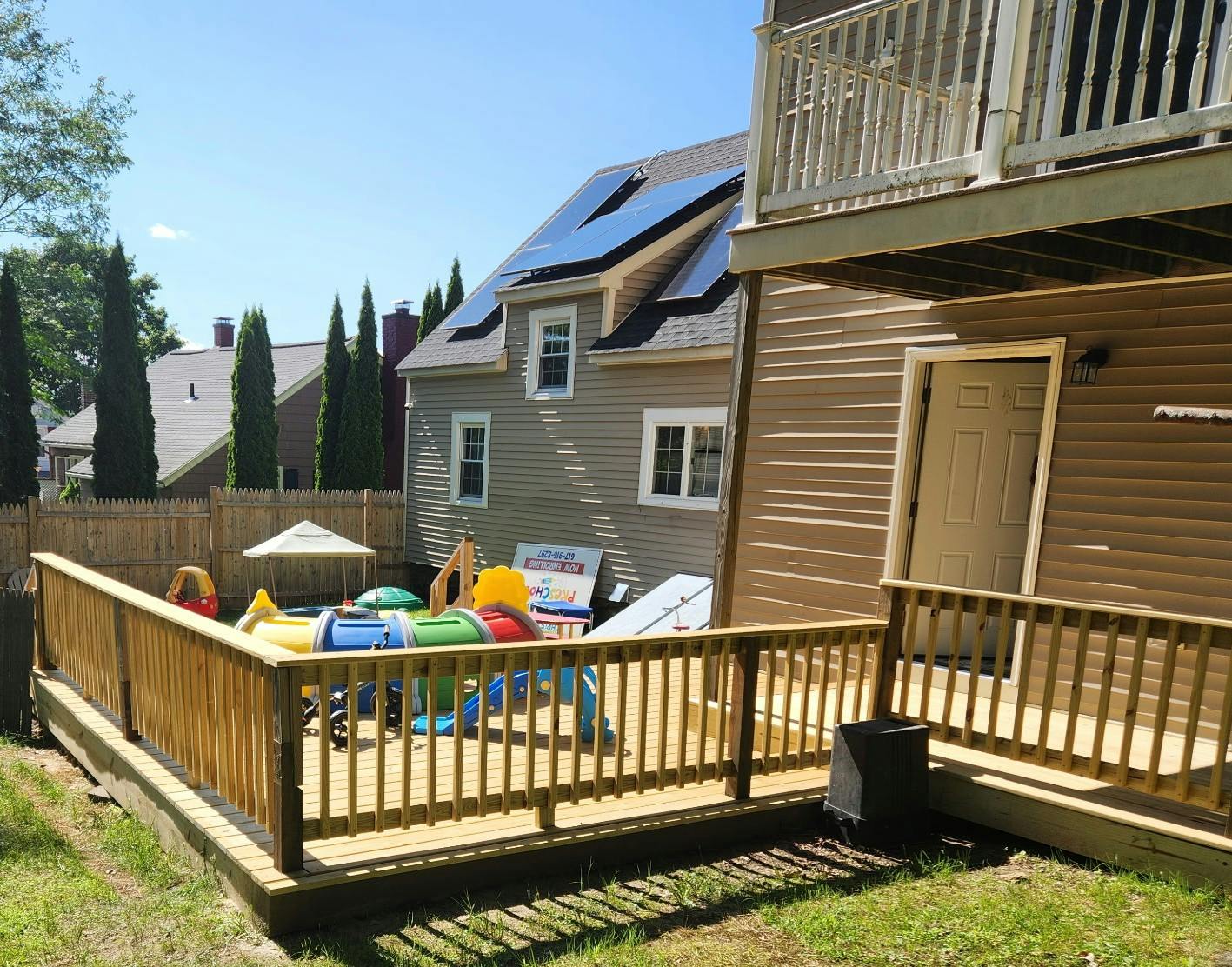 Backyard deck with a play area and a house with solar panels