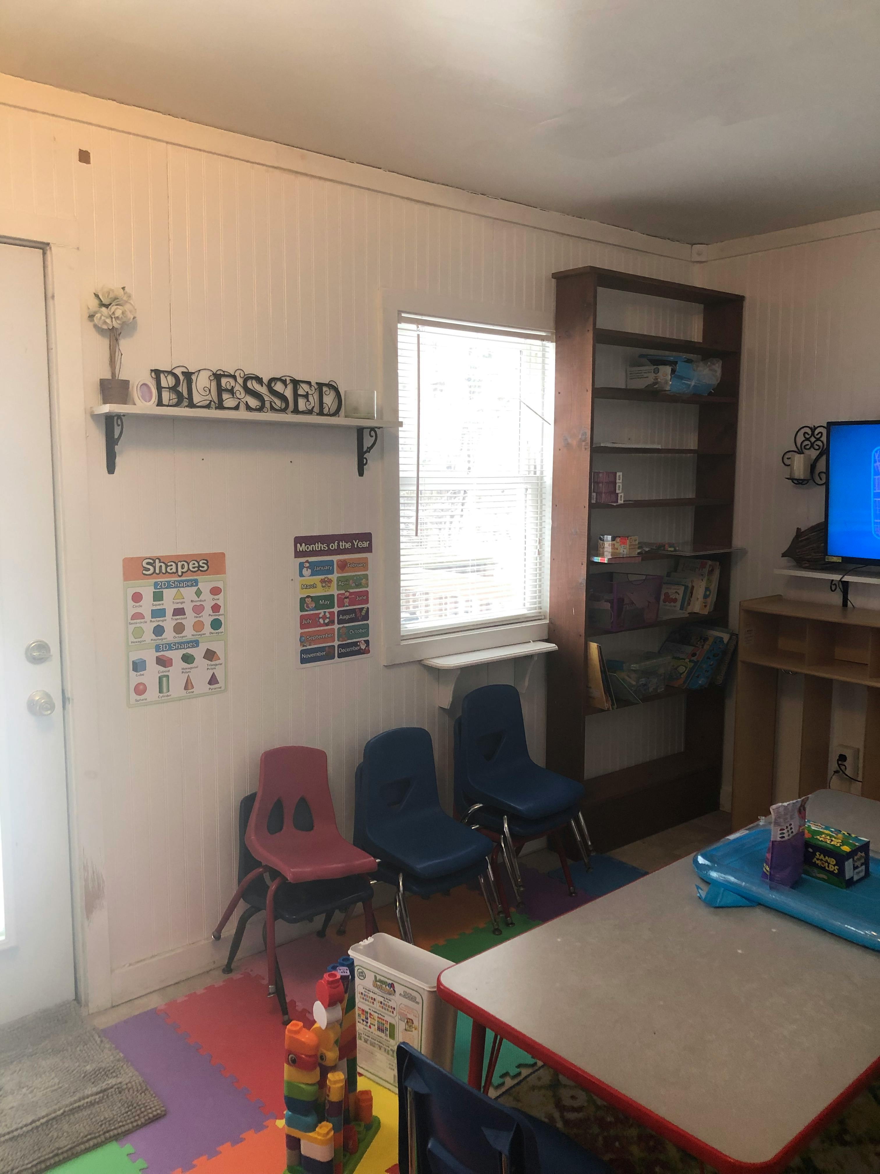 Classroom with small chairs, tables, and a shelf with "BLESSED" sign
