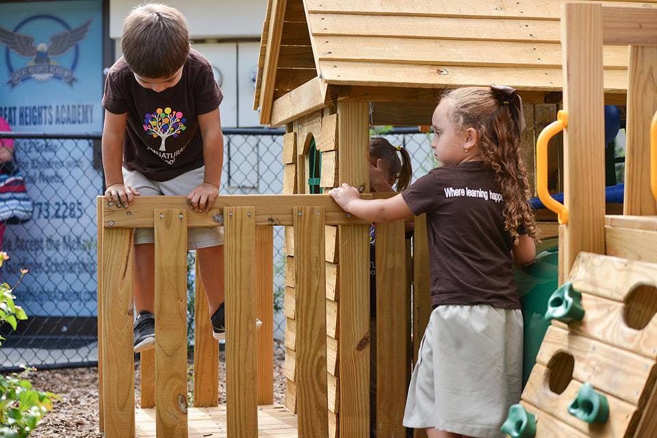 Two children playing on a wooden playground structure