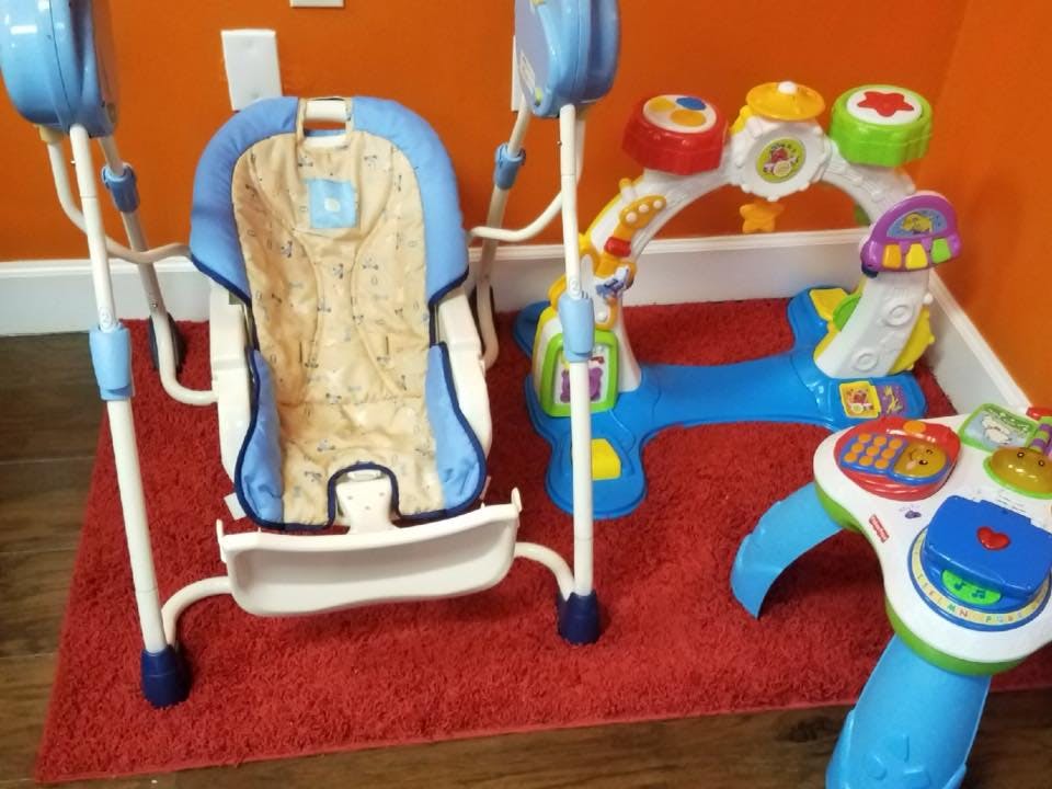 Baby swing and activity toys on a red rug