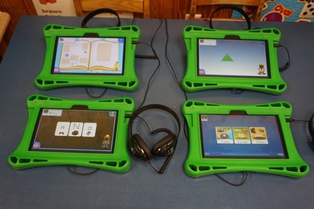 Four green tablets with headphones on a table