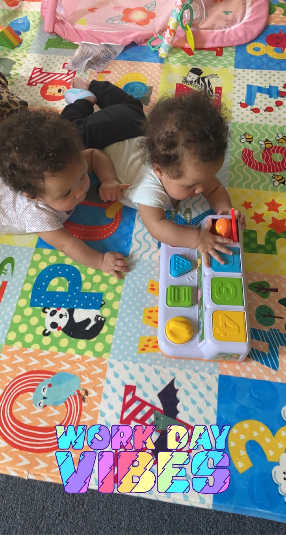 Two children playing with a toy on a colorful mat