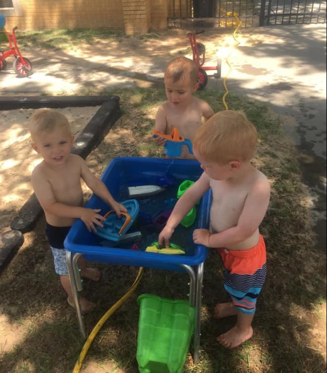 Three children playing at a water table outdoors
