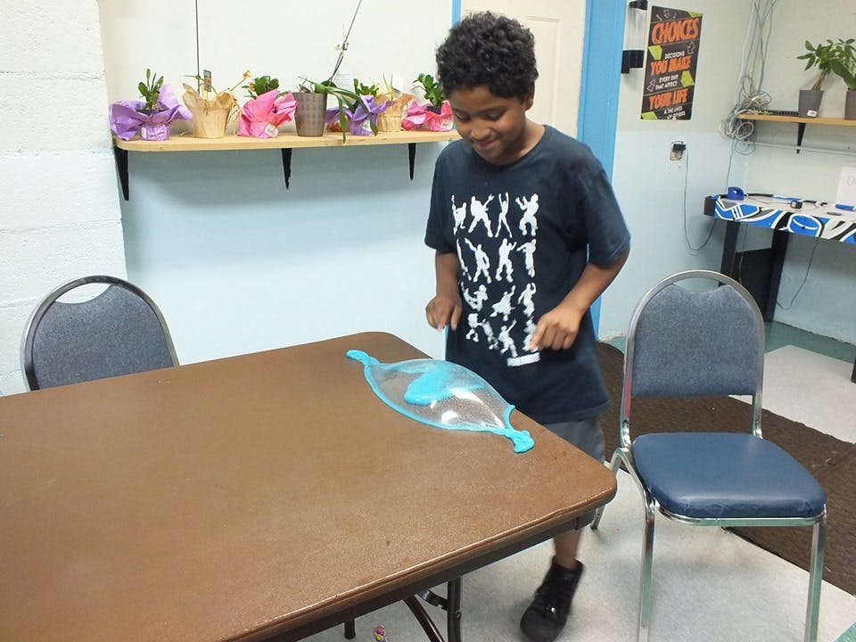 Child standing over a table with a clear toy