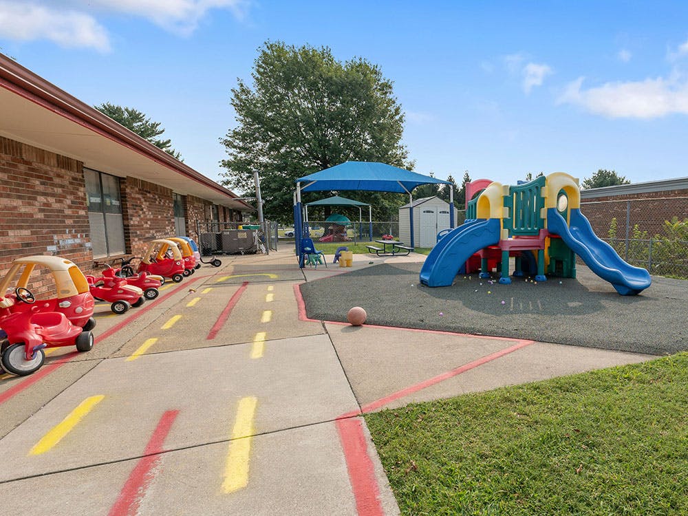 Outdoor playground with slide set and toy cars on a painted road
