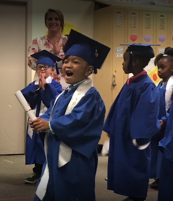 Child in graduation cap and gown holding a diploma