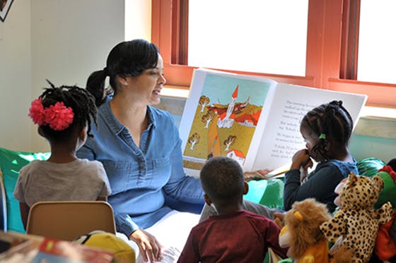 Person reading a book to three children