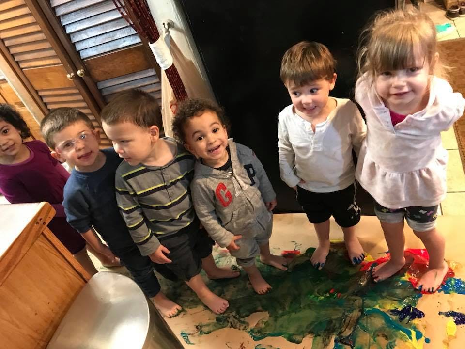 Group of children standing on a paint-splattered surface