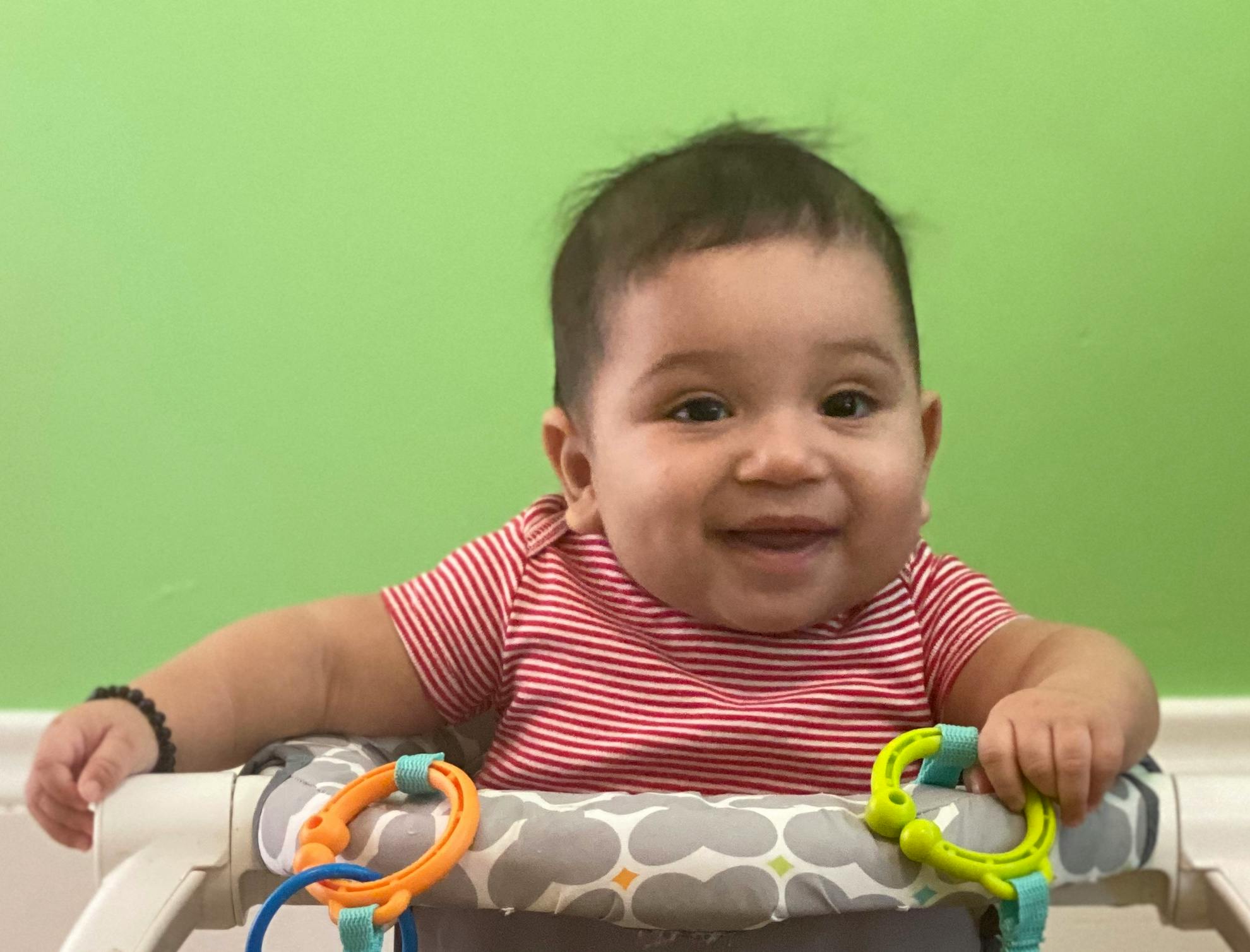 Child in a striped shirt sitting in a baby walker
