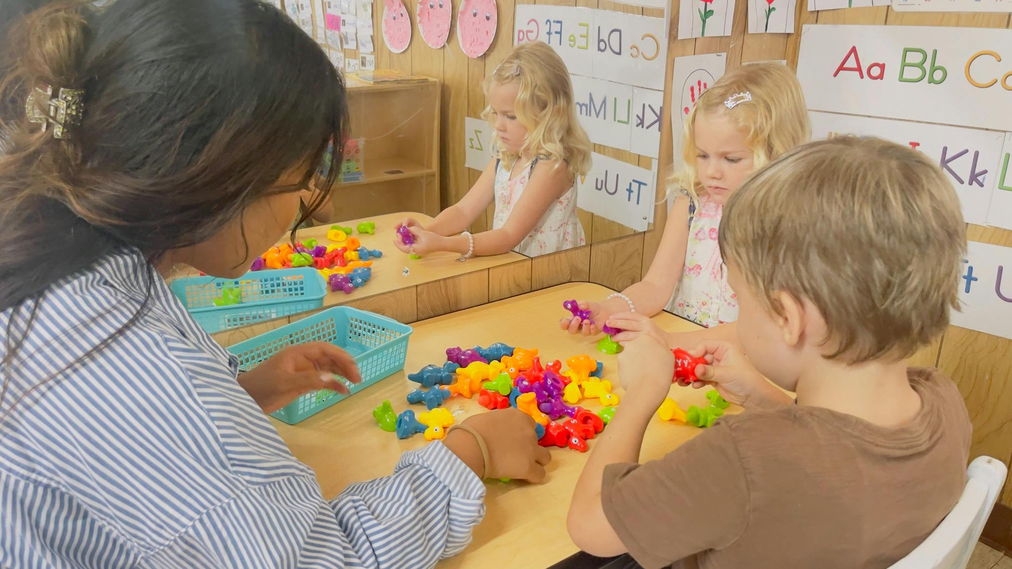 Adult and children playing with colorful toys at a table