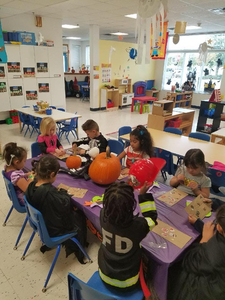 Children sitting at a table with pumpkins in a classroom