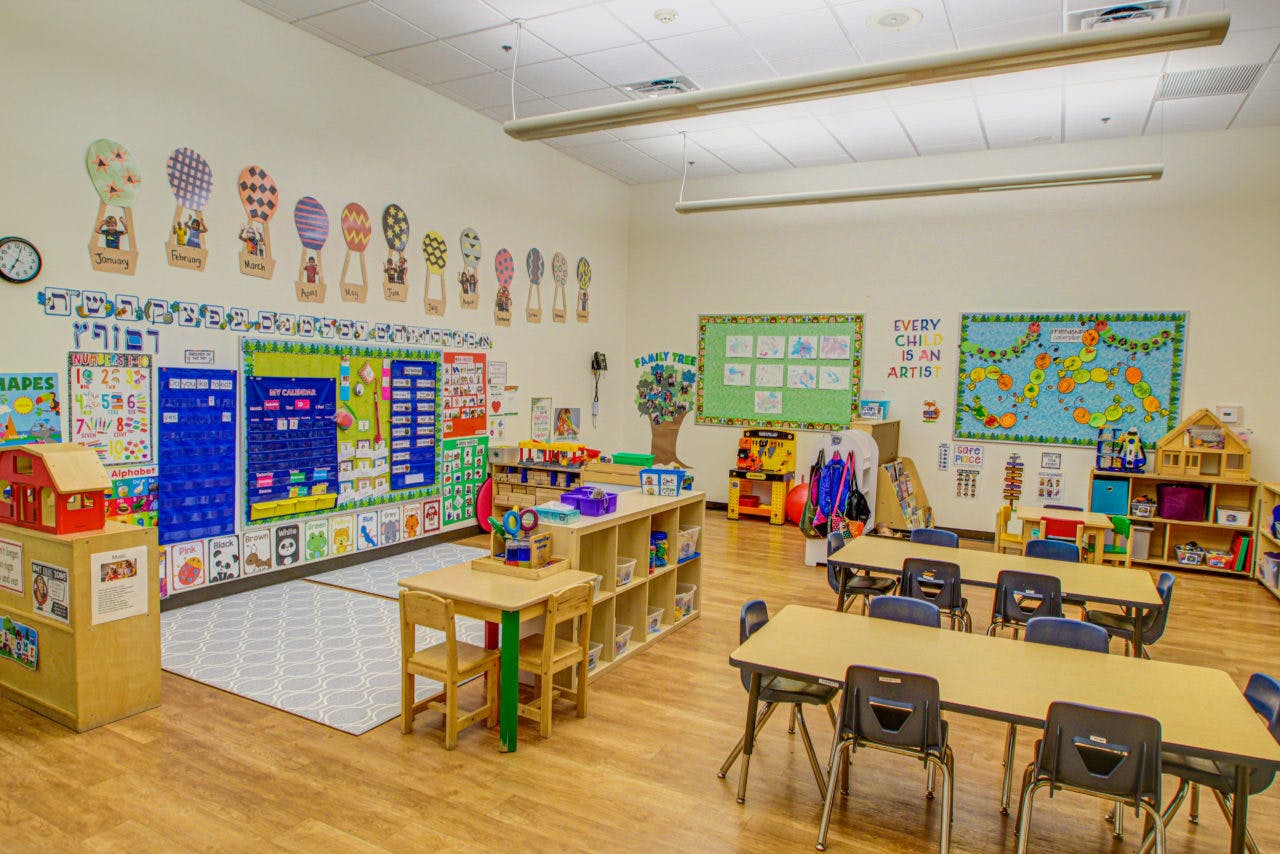 Empty classroom with small tables and chairs, colorful decorations on walls